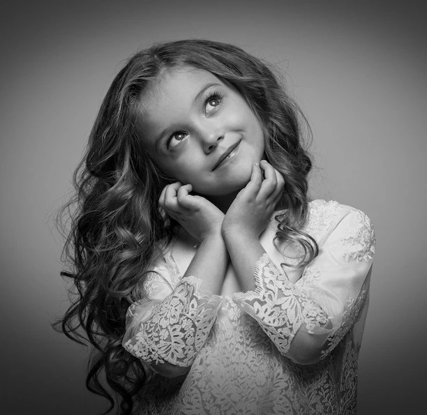 Mädchen mit Locken schaut verträumt nach oben.